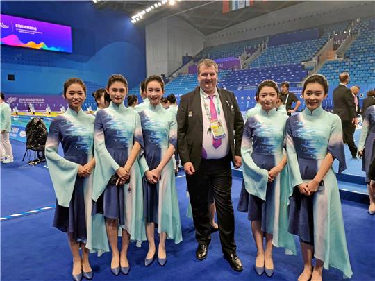 Eingekleidet vom Veranstalter sind die Offiziellen der Asian Para Games leicht zu erkennen. Der Goslarer Kampfrichter Ingmar Hahn in der riesigen Schwimmhalle umringt von einigen Helferinnen. Foto: Privat