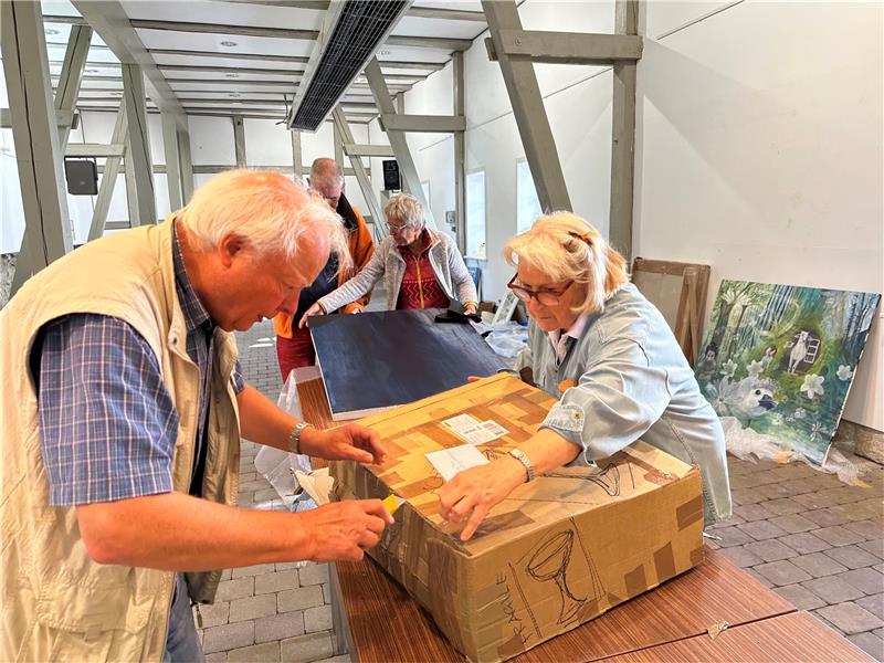 Eingepackt wie ein Westpaket: Vorsichtig schneidet Hans Heckelmann mit dem Teppichmesser das Klebeband durch, Emely Werner hilft ihm. Foto: Eggers