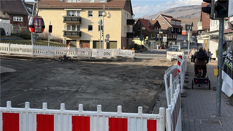 Das Foto zeigt ein Fahrrad mit Anhänger, das auf dem Gehweg entlang einer gesperrten Straße unterwegs ist.