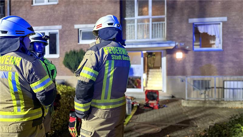 Drei Feuerwehrleute stehen vor dem Haus, in dem sich die hilflose Person befindet. 