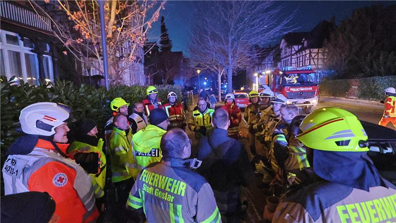 Kräfte von DRK, Polizei und Feuerwehr stehen auf dem Gehweg und besprechen sich mit Christian Hellmeier.