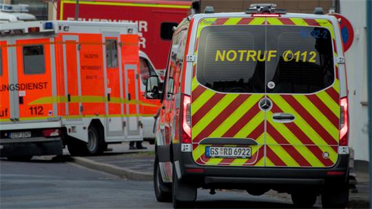 Mehrere Rettungsdienstfahrzeuge stehen im Einsatz in einer Straße. Im Vordergrund ist ein Einsatzfahrzeug mit gelb-roter Warnbeklebung und der Aufschrift ‚Notruf 112‘ zu sehen, dahinter stehen weitere Rettungsfahrzeuge.
