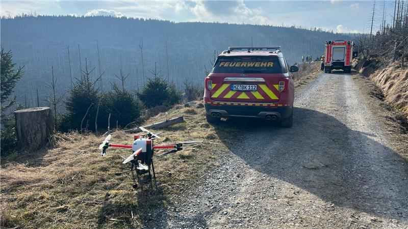 Einsatzfahrzeuge der Feuerwehr und eine Drohne stehen am Wegrand.