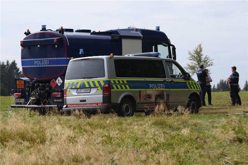 Einsatzfahrzeuge stehen auf einer Fläche. Einsatzkräfte sind bei einem Waldbrand...