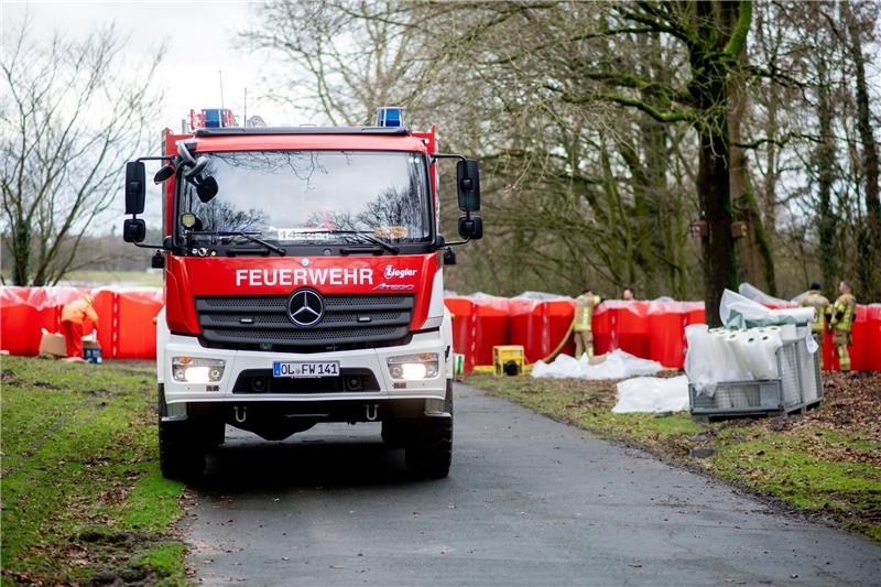 Einsatzkräfte der Feuerwehr befüllen ein mobiles Deichsystem, bestehend aus zahlreichen großen Behältern mit Wasser.