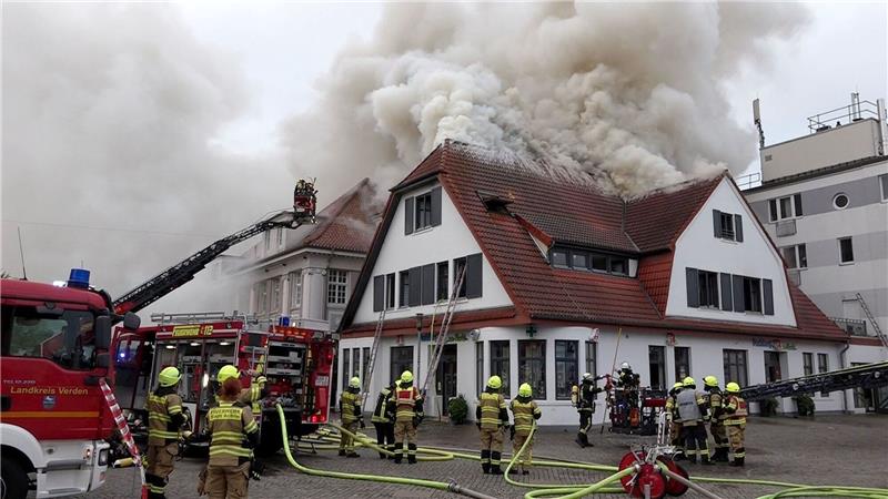 Einsatzkräfte der Feuerwehr bei Löscharbeiten an einem Mehrfamilienhaus in der Innenstadt Achims.