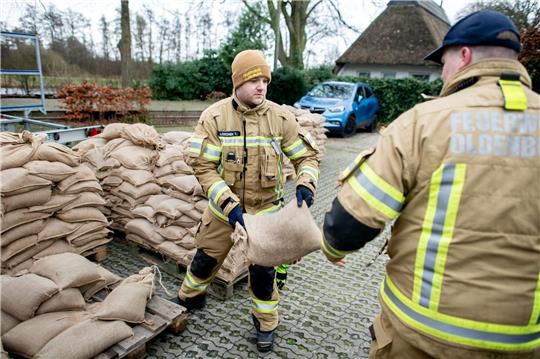 Einsatzkräfte der Feuerwehr geben auf einem Parkplatz Sandsäcke an die Anwohner im Bereich der Hunte am Achterdiek aus.