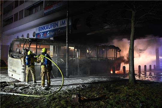 Einsatzkräfte der Feuerwehr löschen in der Silvesternacht im Bezirk Neukölln einen brennenden Bus, der von Unbekannten angezündet worden war.