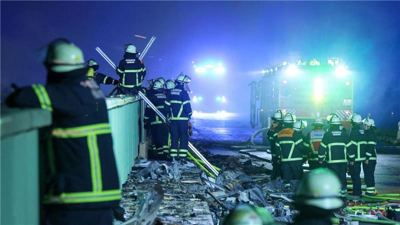Einsatzkräfte der Feuerwehr sind dabei einen Brand in einem Industriegebiet im Hamburger Hafen zu löschen. 