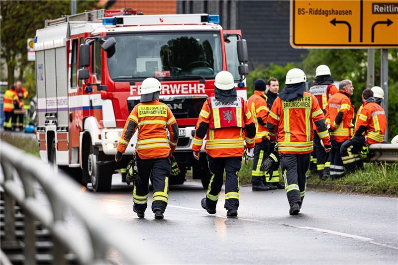Einsatzkräfte der Feuerwehr stehen bei einem Großbrand in einem Braunschweiger Industriegebiet.