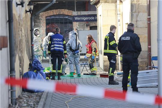 Einsatzkräfte der Feuerwehr stehen im ABC-Schutzanzug auf dem Hauptbahnhof in Wernigerode. Foto: picture alliance/dpa | Matthias Bein