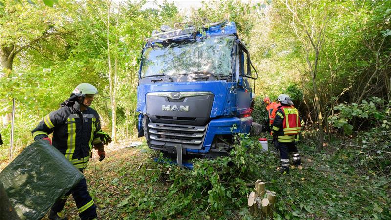Lastwagenunfall auf B3 - Fahrer eingeschlossen und verletzt Einsatzkräfte der Feuerwehr stehen neben dem verunfallten Lkw an der Bundesstraße B3.