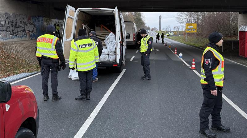 Die Polizei durchsucht ein Fahrzeug. Im Hintergrund stehen weitere Autos