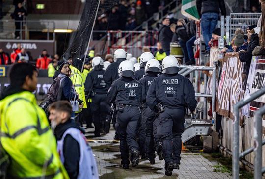 Einsatzkräfte der Polizei laufen auf den Fanblock der Hannoveraner zu.