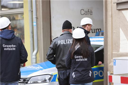 Einsatzkräfte der Polizei und Beamte der Gewerbeaufsicht stehen nach einer Explosion vor einem Fachwerkhaus. Foto: picture alliance/dpa | Matthias Bein