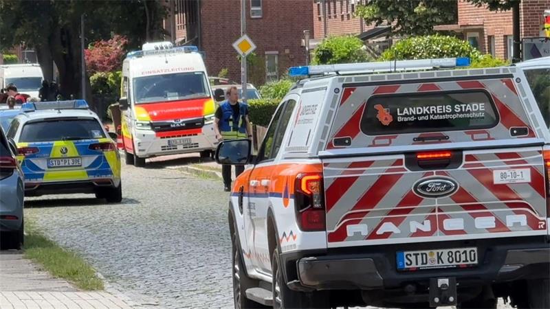 Einsatzkräfte stehen nach der Tat in Stade auf der Straße.