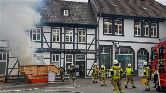 Mehrere Einsatzkräfte stehen vor dem Container und versuchen, den Brand einzudämmen. 