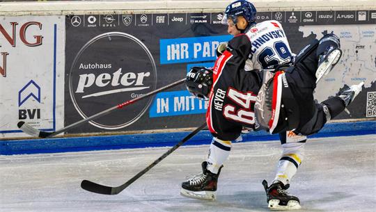 Zwei Eishockeyspieler kämpfen um den Puck, einer trägt schwarze Ausrüstung mit der Nummer 64, der andere weiße Ausrüstung mit der Nummer 69