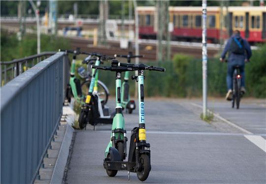 Elektroroller verschiedener Anbieter stehen nahe dem Berliner Bahnhof Ostkreuz auf einem Gehweg.