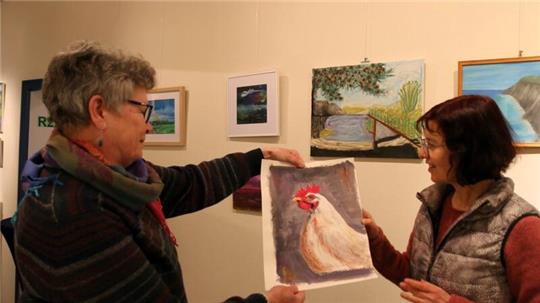 Elisabeth May (l.) präsentiert ihr Huhn. Ulrike Bosse ist begeistert.
