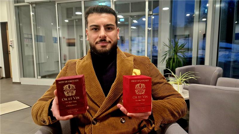 Emil Alkountar hält im Foyer des Gründungszentrums zwei Verpackungen seiner Parfums in der Hand.