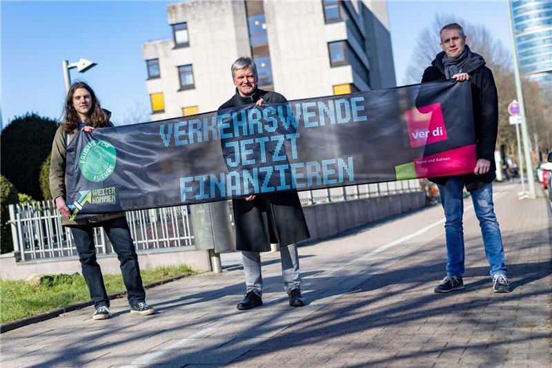 Warum die Klimabewegung den ÖPNV-Warnstreik unterstützt Emil Görtzen (l-r), Fridays for Future, Jürgen Schirmer, Gewerkschaft Verdi, und Patrick Steinbach, Verkehrsbetrieb BoGeStra, stehen mit einem Banner zum gemeinsamen Aktionstag vor der Verdi-Zentrale in Bochum.