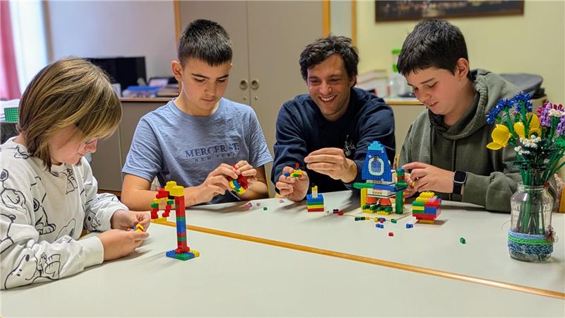Emily Grimm, Artem Dobrovolskyi und Jaden Meyer (von links) aus der sechsten Klasse basteln zusammen mit Schulleiter Quint Gembus die ersten Modelle aus Legosteinen.