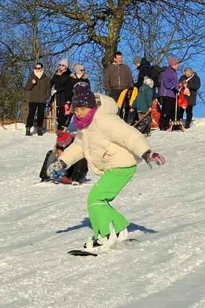 Ein junges Mädchen fährt Snowboard.