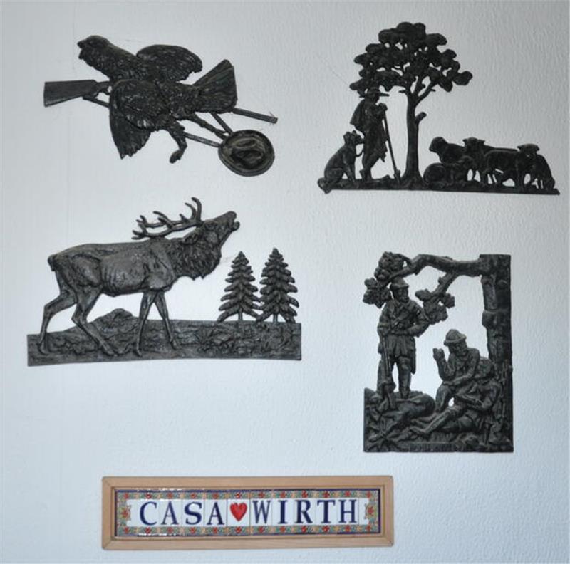 Vier schwarze Wandreliefs mit Jagdmotiven und ein Schild mit der Aufschrift 'CASA WIRTH'