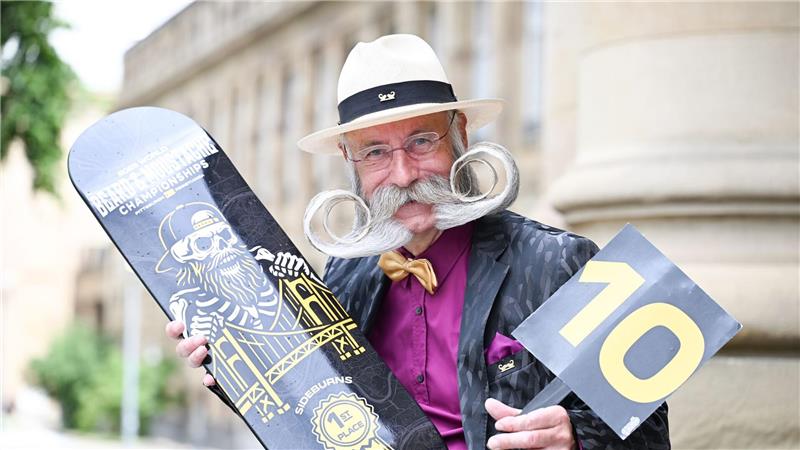 So küsst es sich mit Weltmeister-Bart Er präsentiert seine Siegertrophäe und eine Wertungstafel mit der Maximalpunktzahl 10.