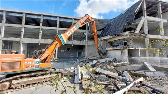 Er wirbelt bisweilen Staub auf: Ein Bagger frisst sich durch die Überreste des alten Real-Markts. Foto: Neuendorf