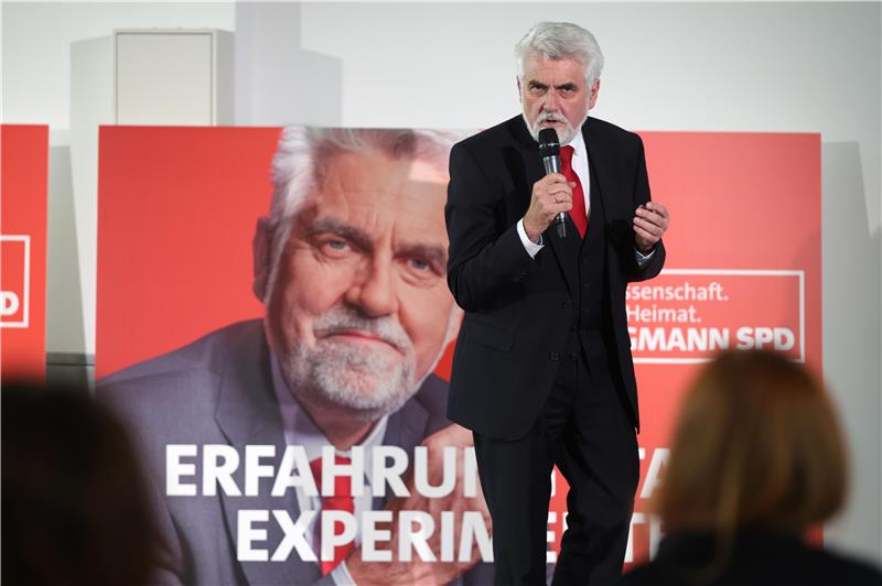 Ein Mann steht auf einer Bühne und spricht in ein Mikrofon.