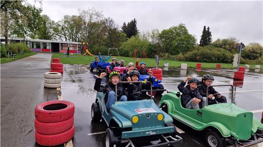 Kinder fahren in kleinen Elektroautos auf einer nassen Rennstrecke im Freien