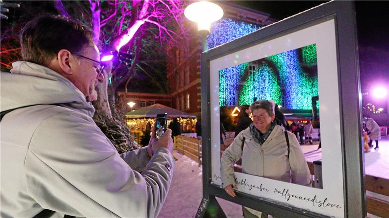Ein Mann fotografiert mit dem Handy an einem Fotopunkt eine Frau.