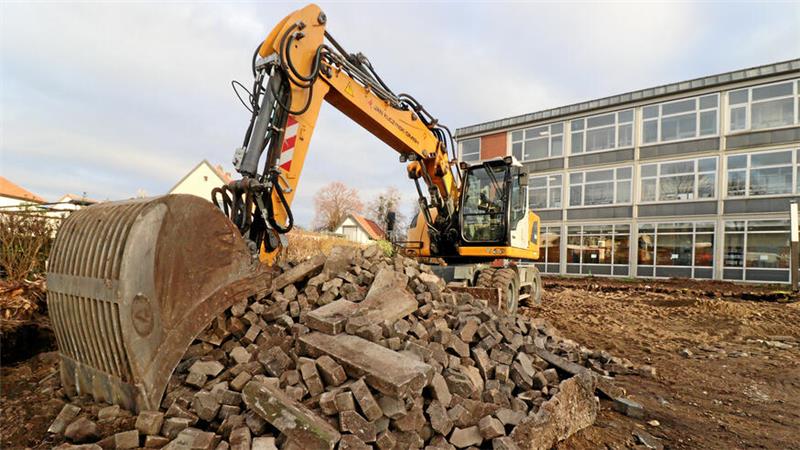 Bagger kratzt Pflastersteine zusammen