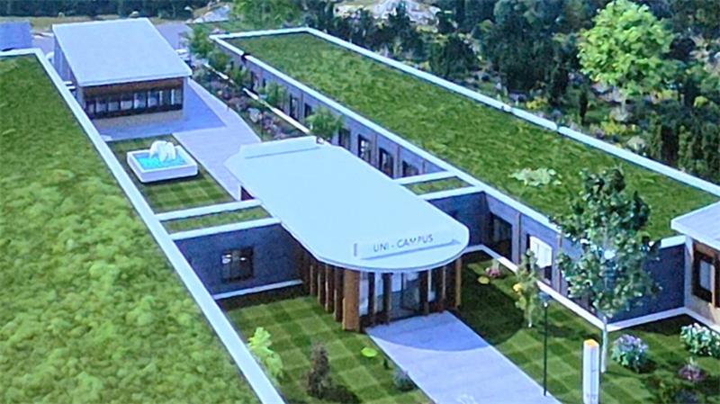 Luftaufnahme eines modernen, flach gebauten Gebäudekomplexes mit begrünten Dächern und einem kleinen Wasserbecken im Innenhof