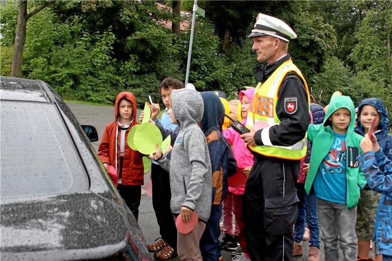 Erstklässler der Grundschule Clausthal verteilen unter Aufsicht des Polizisten Ralf Buchmeier Smileys an Autofahrer. Fotos: Knoke