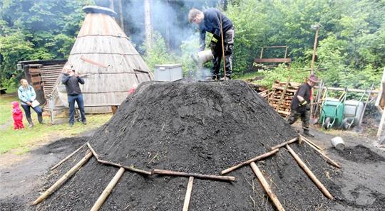 Es geht los: Köhlermeister Simon Wiese kippt die Glut in den Quandel, das ist der Feuerschacht in der Mitte des Meilers.