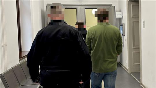 Der 48-Jährige im grünen Pulli wird von zwei Justizbeamten in den Gerichtssaal geführt.