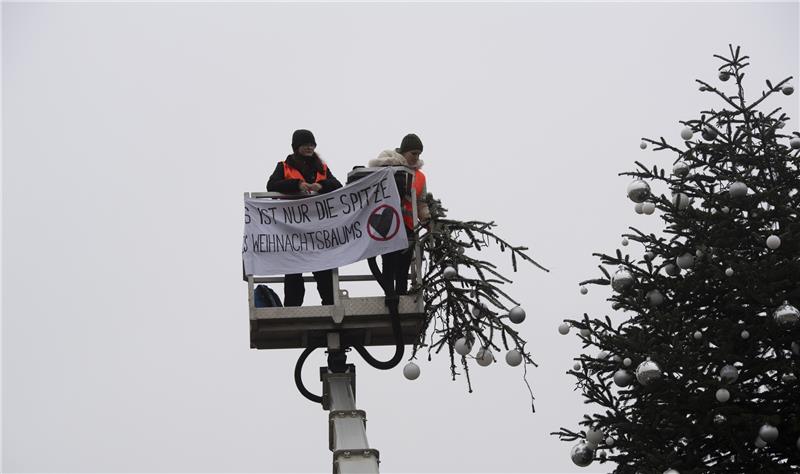 Weihnachtsbaum abgesägt: Geldstrafe für Frau aus Helmstedt „Es ist nur die Spitze des Weihnachtsbaums“ steht auf dem Transparent der Aktivisten der „Letzten Generation“. Zwei Aktivisten der Umweltschutzgruppe fuhren mit einem Hubwagen vor dem Tannenbaum auf dem Pariser Platz am Brandenburger Tor. Sie entrollten ein Transparent und entfernten dann die Spitze des Weihnachtsbaums. Foto: picture alliance/dpa | Paul Zinken