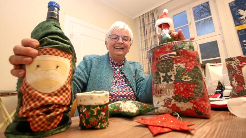 Es kommt auf die Verpackung an: Christine Stegmann mit der großen für die Glühweinflasche und dem kleinen Mützchen fürs Piccolöchen, die sie aus einer Tüte herauszieht.