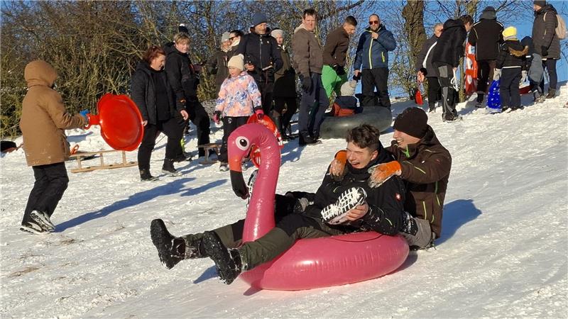 Zwei Personen fahren auf einem aufblasbaren Flamingo talwärts.