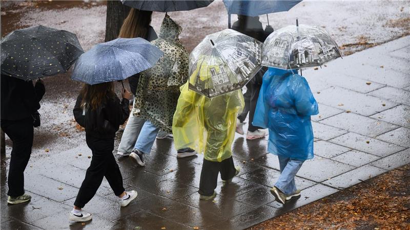 Es wird Regen geben! Jugendliche halten Schirme bei Regenwetter in Dresden.