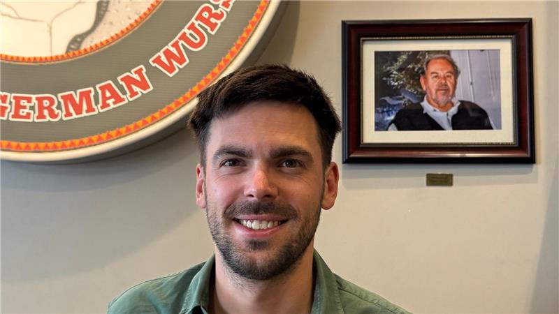 Fabian Förster steht vor einem Foto seines Großvaters, nach dem „Dieters Grill“ benannt wurde.