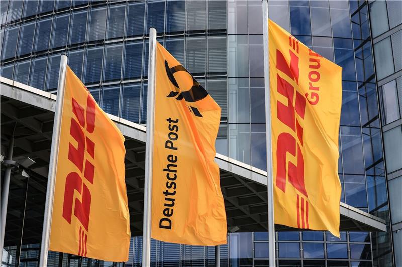 Dumping? Behörde leitet Verfahren gegen Post-Tochter ein Fahnen von Post und DHL wehen vor der Zentrale der DHL Group - Deutsche Post in Bonn.