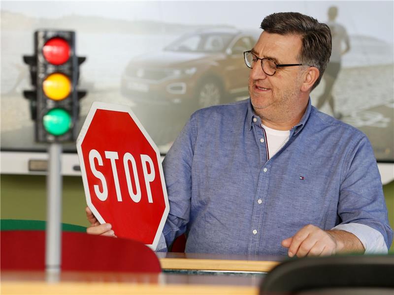 Fahrschüler müssen oft lange auf Prüfung warten Fahrlehrer Horst Wintgen sitzt mit Ampel und Verkehrsschild im Übungsraum seiner Fahrschule.