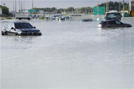 Fahrzeuge stehen verlassen im Hochwasser auf einer Hauptstraße in Dubai.
