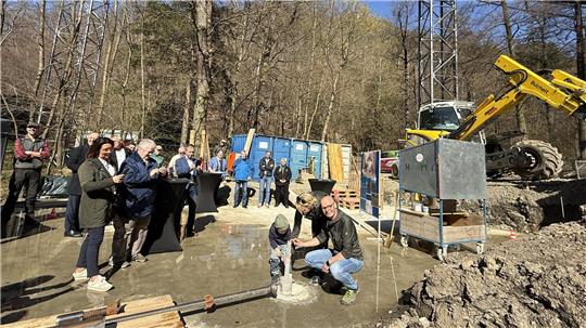 Familie Kolb versenkt symbolisch ein GZ-Glücjsschweinchen im Fundament der Wipfelerlebniswelt.
