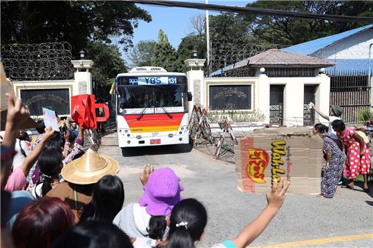 Familienmitglieder und Freunde von Häftlingen stehen vor dem Insein-Gefängnis in Yangon, als ein Bus mit Freigelassenen vom Gelände fährt.