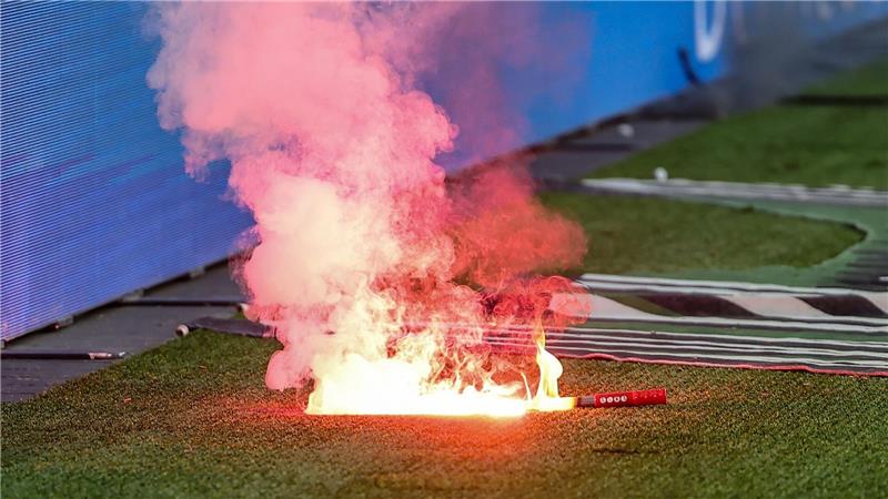 Fans von Wolfsburg werfen Leuchtfackeln auf den Platz.
